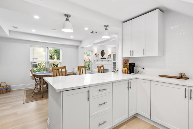 kitchen with kitchen peninsula, light hardwood / wood-style flooring, white cabinetry, and hanging light fixtures