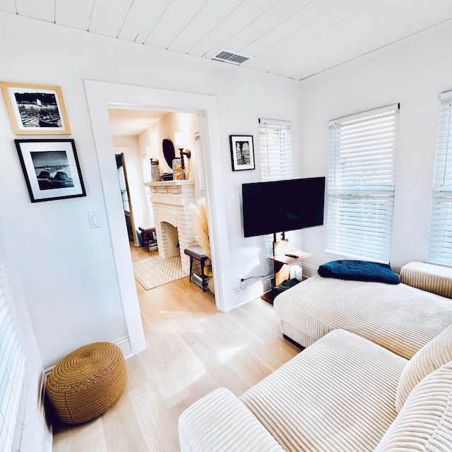 living room featuring a brick fireplace, wood ceiling, and light hardwood / wood-style flooring