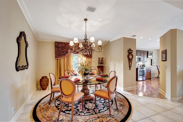 dining room with light tile flooring, ornamental molding, and a chandelier