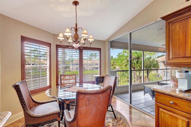 dining room with lofted ceiling, plenty of natural light, light wood-type flooring, and an inviting chandelier