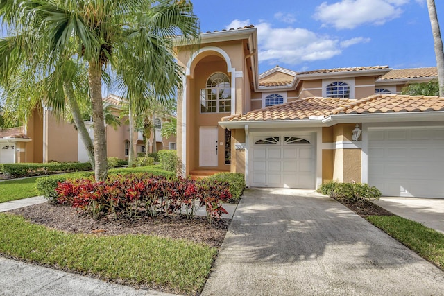 mediterranean / spanish home featuring stucco siding, a garage, driveway, and a tiled roof