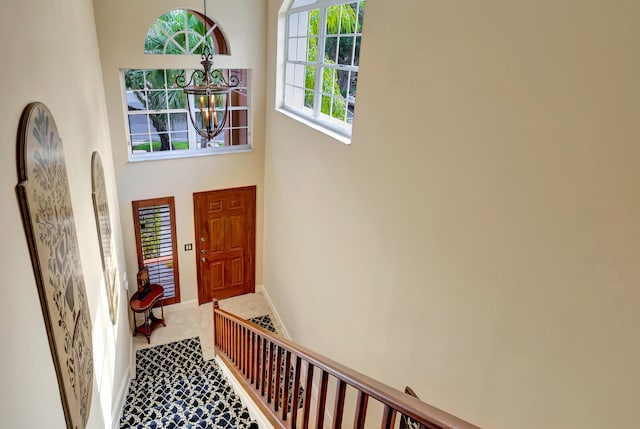 carpeted entryway featuring a high ceiling and a notable chandelier