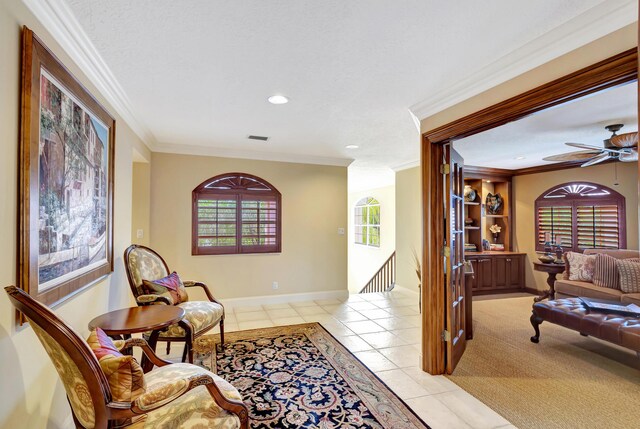 carpeted living room featuring ornamental molding, ceiling fan, and a textured ceiling