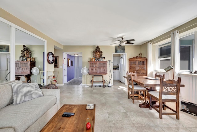 living area featuring baseboards, a ceiling fan, and light tile patterned flooring