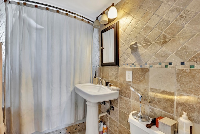 full bathroom with toilet, decorative backsplash, and tile walls