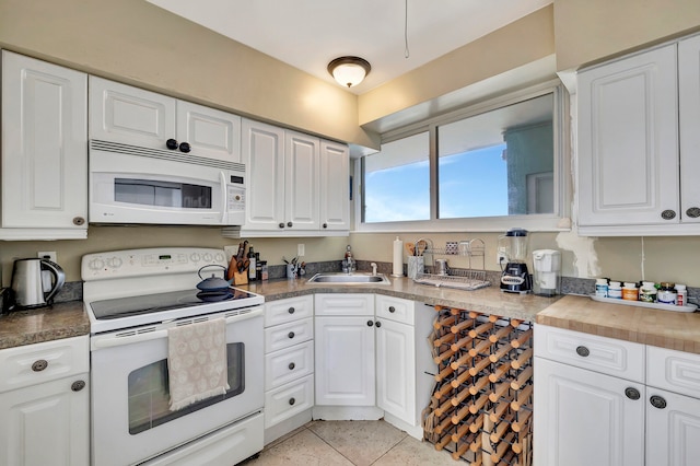 kitchen featuring light tile patterned floors, white appliances, a sink, and white cabinetry