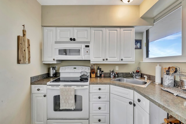 kitchen featuring white appliances, white cabinets, and a sink