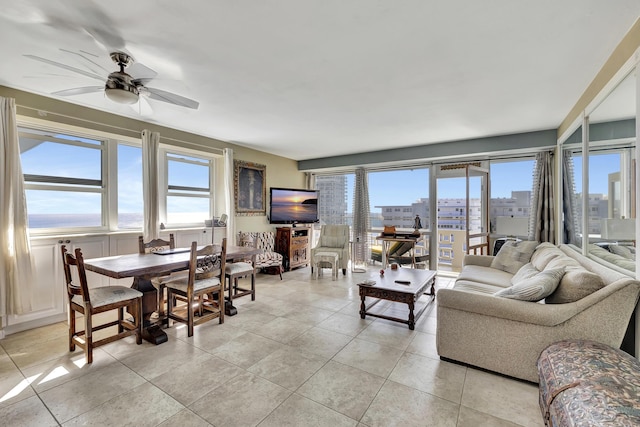 living area with light tile patterned floors and ceiling fan