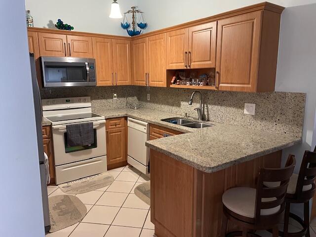 kitchen featuring kitchen peninsula, backsplash, sink, dishwasher, and electric range oven