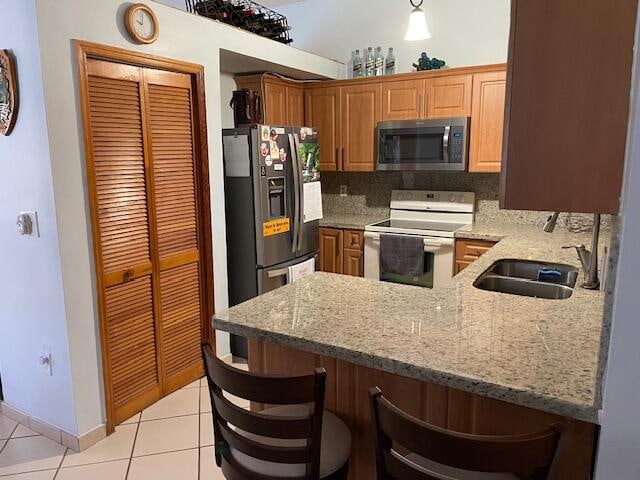 kitchen with backsplash, a kitchen breakfast bar, stainless steel appliances, and light tile floors