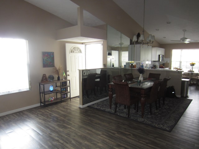 dining space featuring ceiling fan with notable chandelier, high vaulted ceiling, and dark hardwood / wood-style flooring