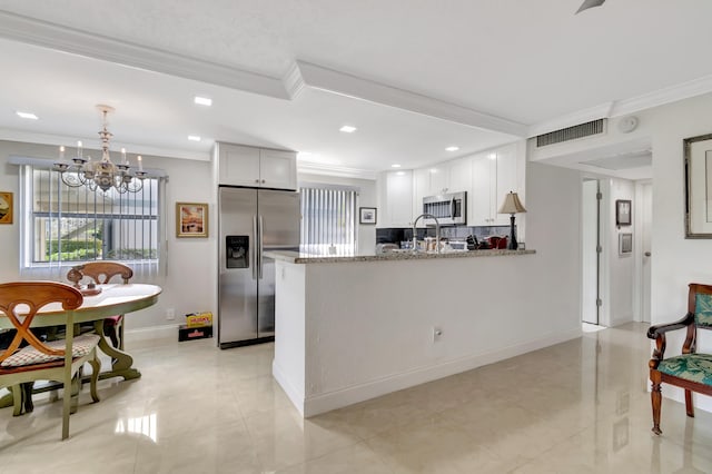 kitchen with white cabinets, a chandelier, stainless steel appliances, light stone countertops, and decorative light fixtures