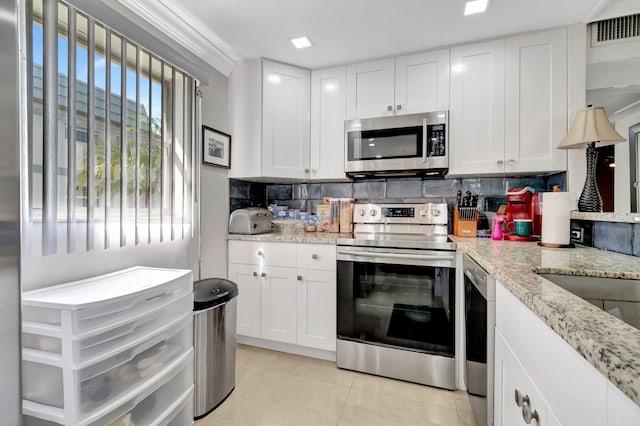 kitchen with appliances with stainless steel finishes, white cabinetry, tasteful backsplash, and light stone counters