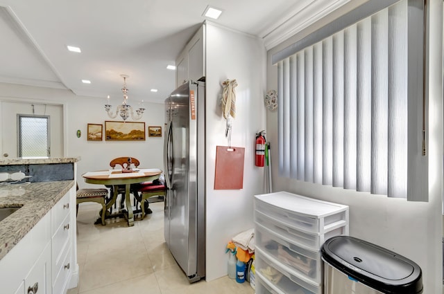 kitchen with stainless steel fridge, pendant lighting, white cabinets, light tile flooring, and light stone countertops