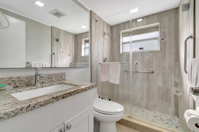 bathroom with an enclosed shower, vanity, tile floors, and toilet