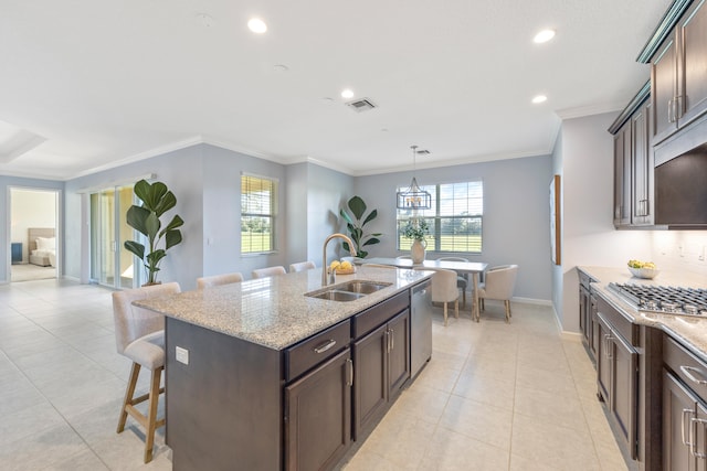 kitchen with light stone countertops, appliances with stainless steel finishes, a kitchen breakfast bar, sink, and an island with sink