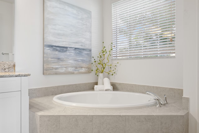 bathroom with vanity, a relaxing tiled tub, and a wealth of natural light