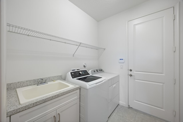 laundry area with sink, cabinets, washing machine and dryer, a textured ceiling, and light tile patterned floors