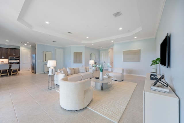 living room featuring a tray ceiling, ornamental molding, and light tile patterned flooring