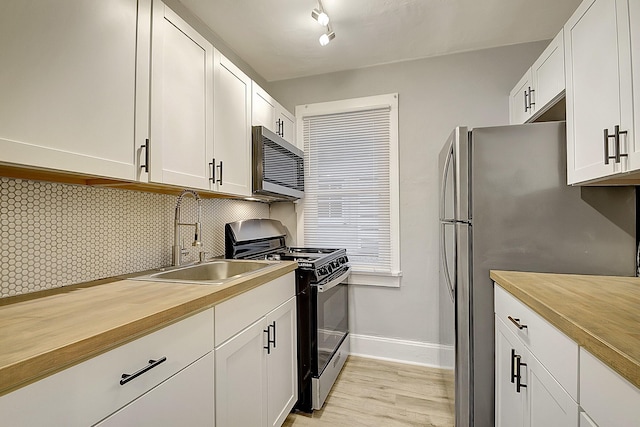 kitchen with light hardwood / wood-style floors, sink, white cabinetry, decorative backsplash, and stainless steel appliances