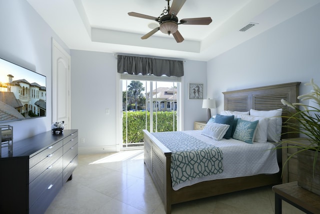 bedroom with a raised ceiling, access to exterior, and ceiling fan