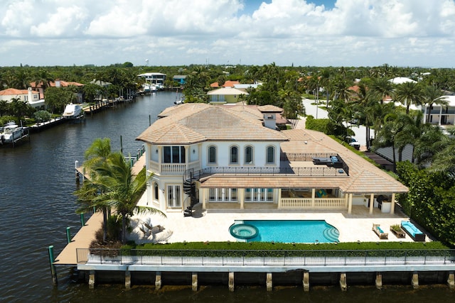 rear view of property with a balcony, a patio, a fenced in pool, and a water view