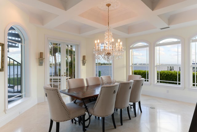 dining space with light tile patterned floors, a notable chandelier, and a water view