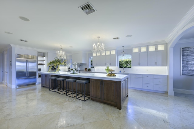 kitchen featuring a chandelier, hanging light fixtures, a large island, white cabinetry, and stainless steel built in refrigerator