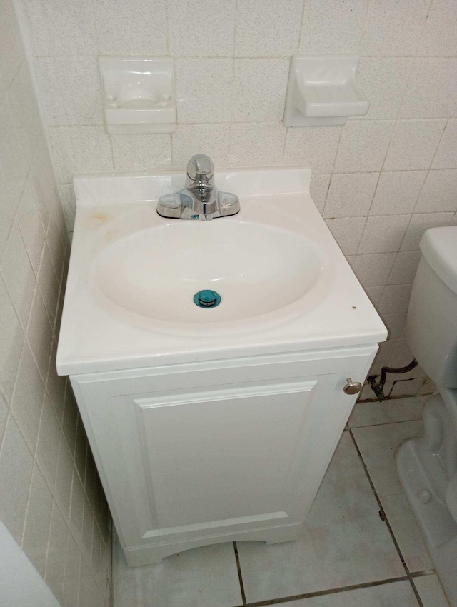 bathroom featuring tile walls, tile floors, toilet, and vanity