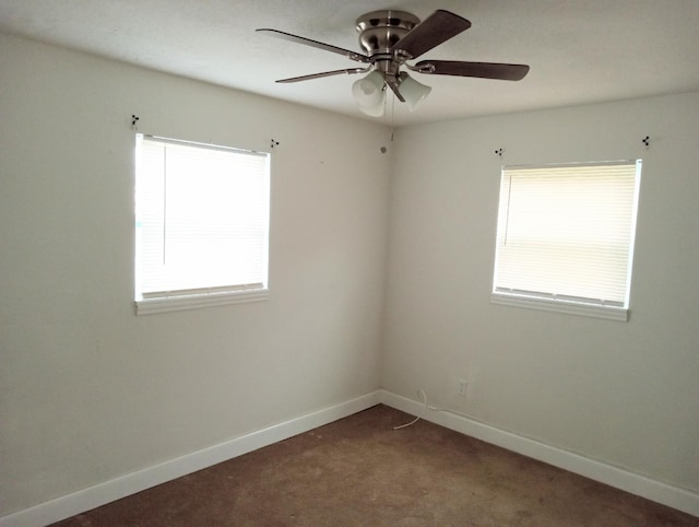 carpeted spare room featuring plenty of natural light and ceiling fan