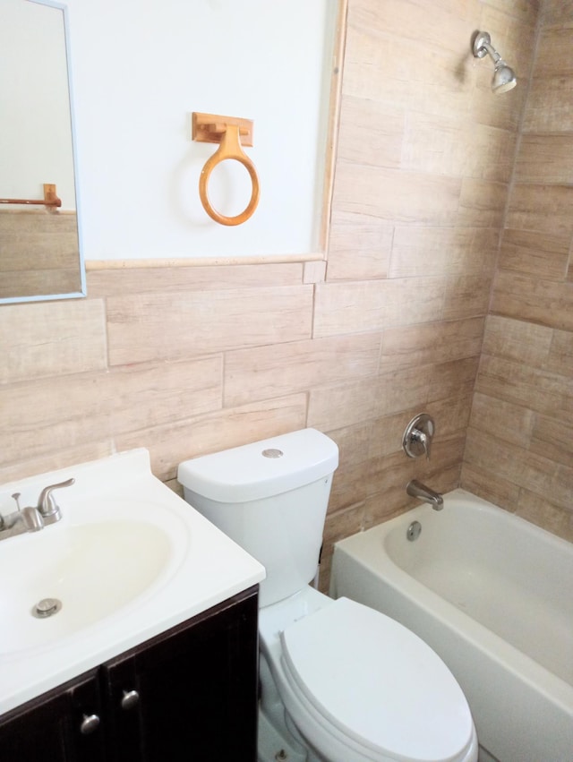 full bathroom featuring tile walls, toilet, vanity, and tiled shower / bath