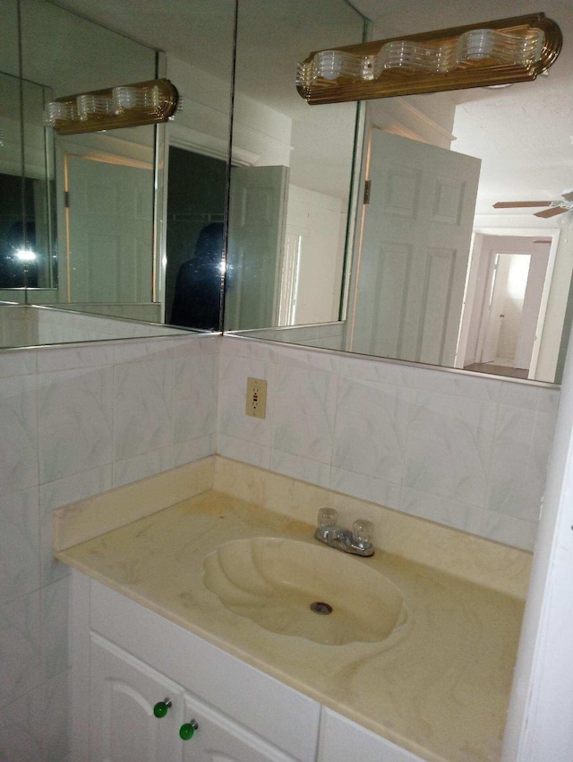 bathroom featuring backsplash, large vanity, ceiling fan, and tile walls