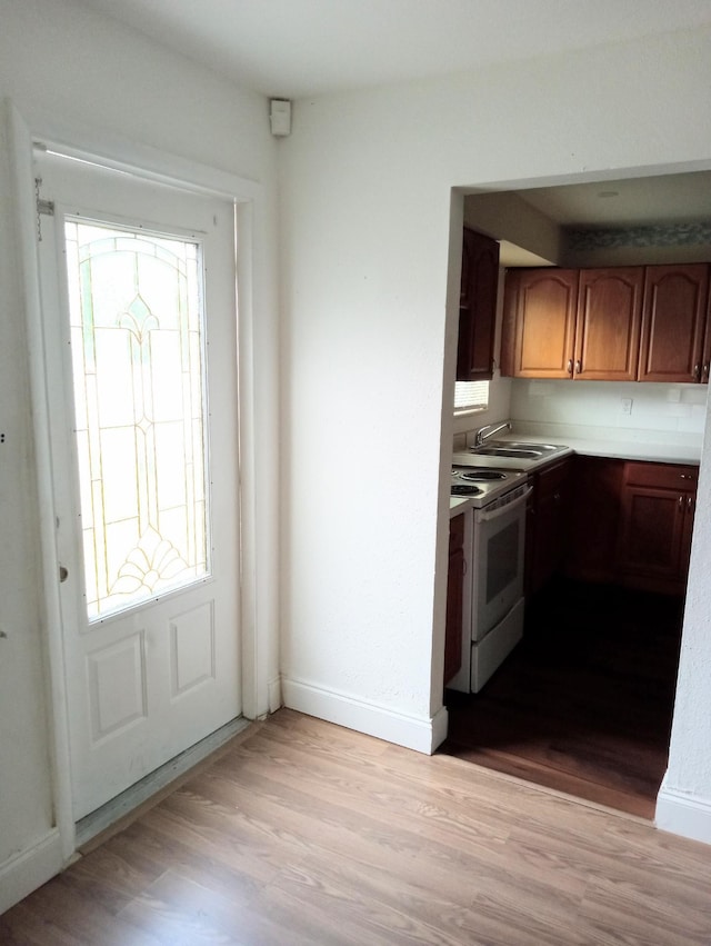 kitchen featuring electric range, sink, and light hardwood / wood-style flooring