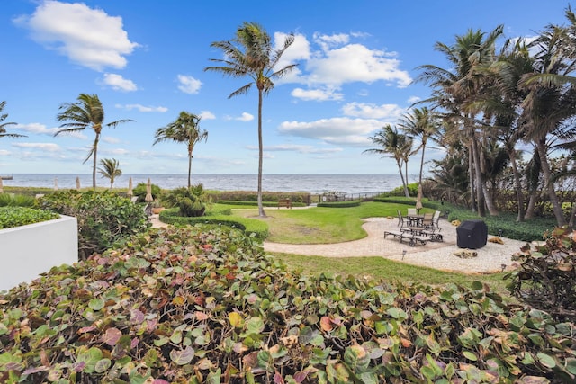 view of home's community with a patio area, a lawn, and a water view