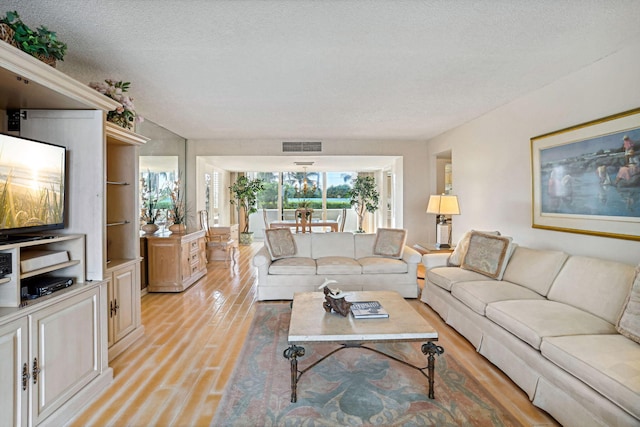 living room featuring a textured ceiling, built in shelves, and light wood-type flooring