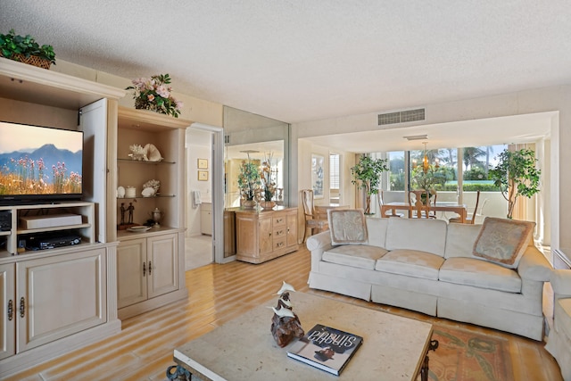 living room featuring light hardwood / wood-style floors, a textured ceiling, and built in shelves