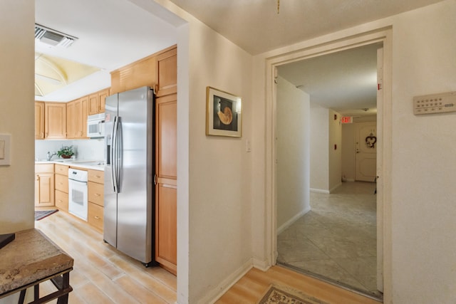 kitchen featuring white appliances, light brown cabinets, sink, and light tile floors