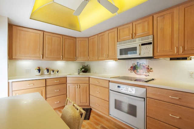 kitchen featuring white appliances, ceiling fan, sink, backsplash, and light hardwood / wood-style floors