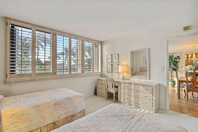 bedroom with multiple windows, light hardwood / wood-style floors, a notable chandelier, and a textured ceiling