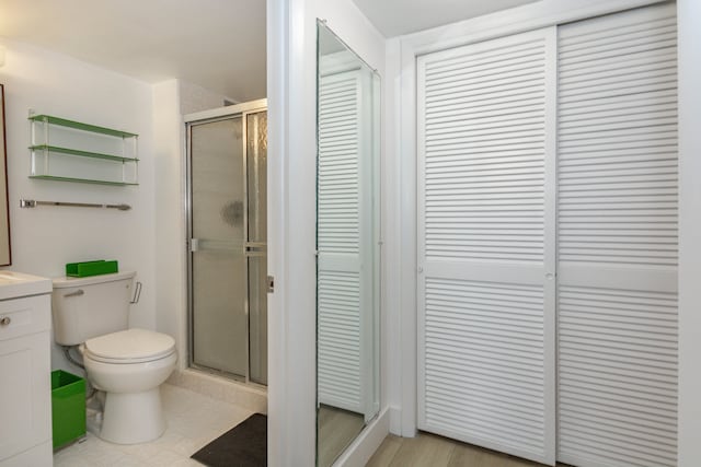 bathroom featuring tile patterned floors, toilet, vanity, and a shower with shower door