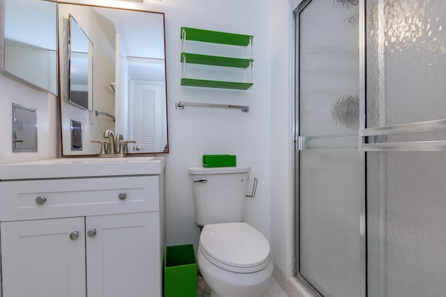 bathroom with an enclosed shower, toilet, vanity, and tile patterned floors