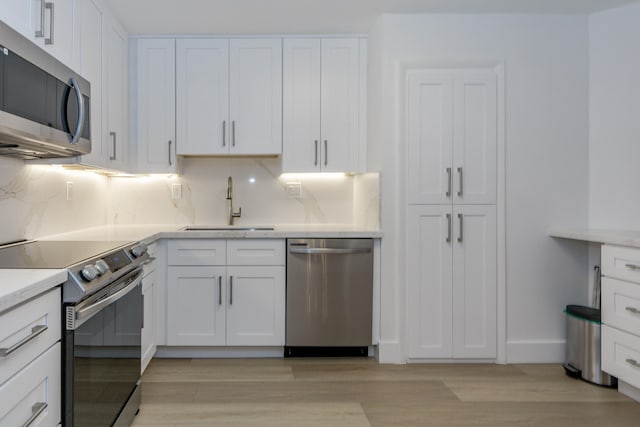 kitchen featuring sink, stainless steel appliances, light hardwood / wood-style floors, and white cabinets