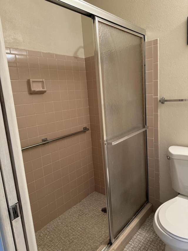 bathroom with toilet, tile patterned floors, and walk in shower