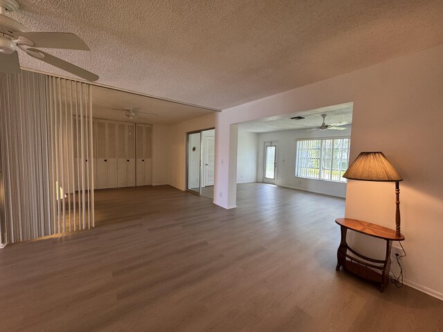 spare room with dark hardwood / wood-style floors, ceiling fan with notable chandelier, and a textured ceiling