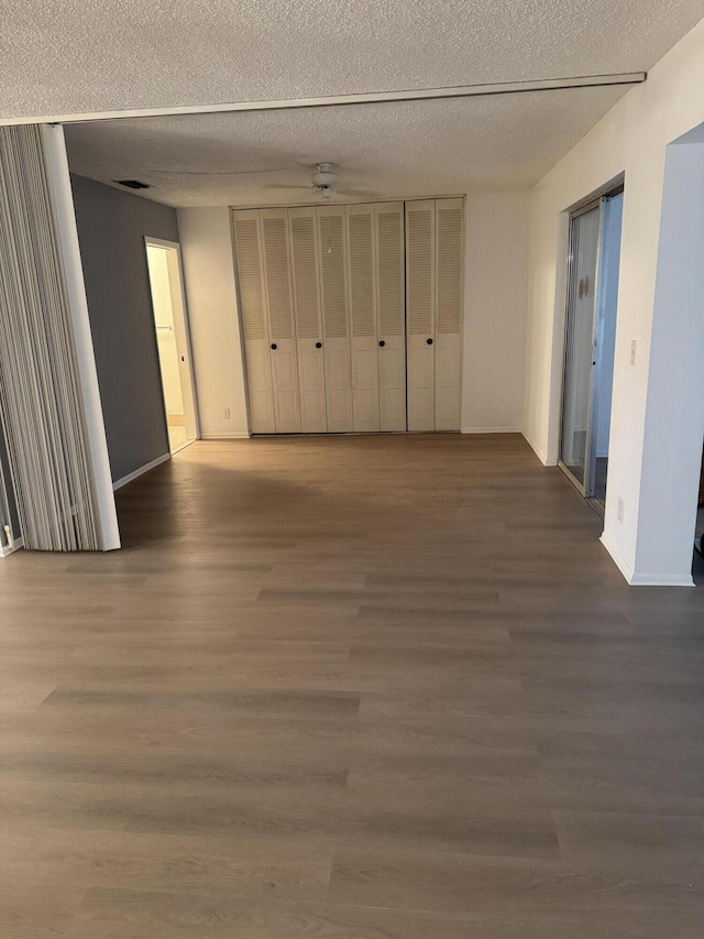 unfurnished room featuring a textured ceiling and dark hardwood / wood-style flooring