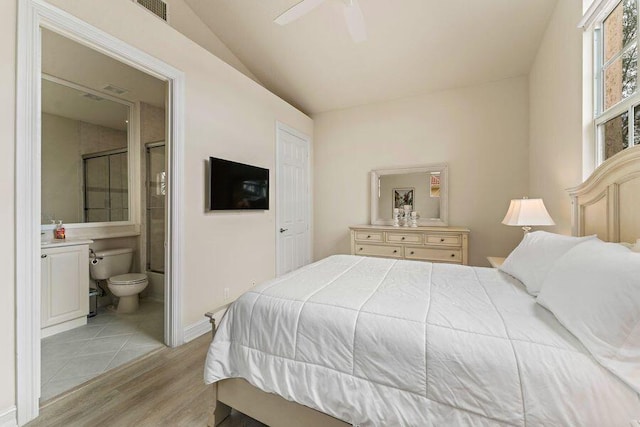 bedroom featuring light tile floors, connected bathroom, lofted ceiling, and ceiling fan