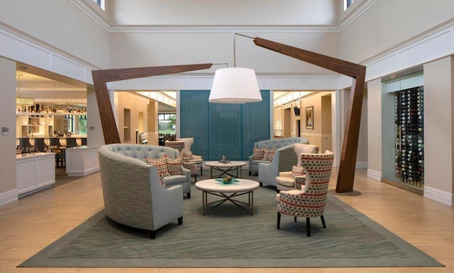 living room featuring light hardwood / wood-style floors, ornamental molding, and a high ceiling