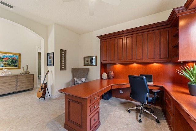 tiled office space with ceiling fan and built in desk