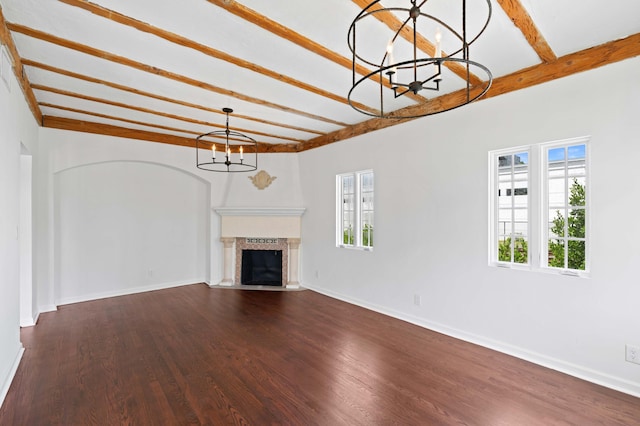 unfurnished living room with beamed ceiling, dark wood-type flooring, and an inviting chandelier