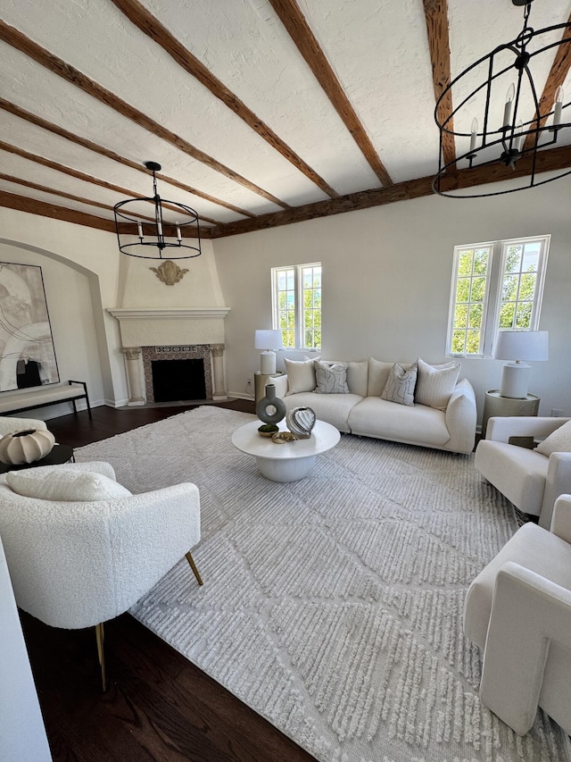 living room with beamed ceiling, a healthy amount of sunlight, hardwood / wood-style floors, and a large fireplace